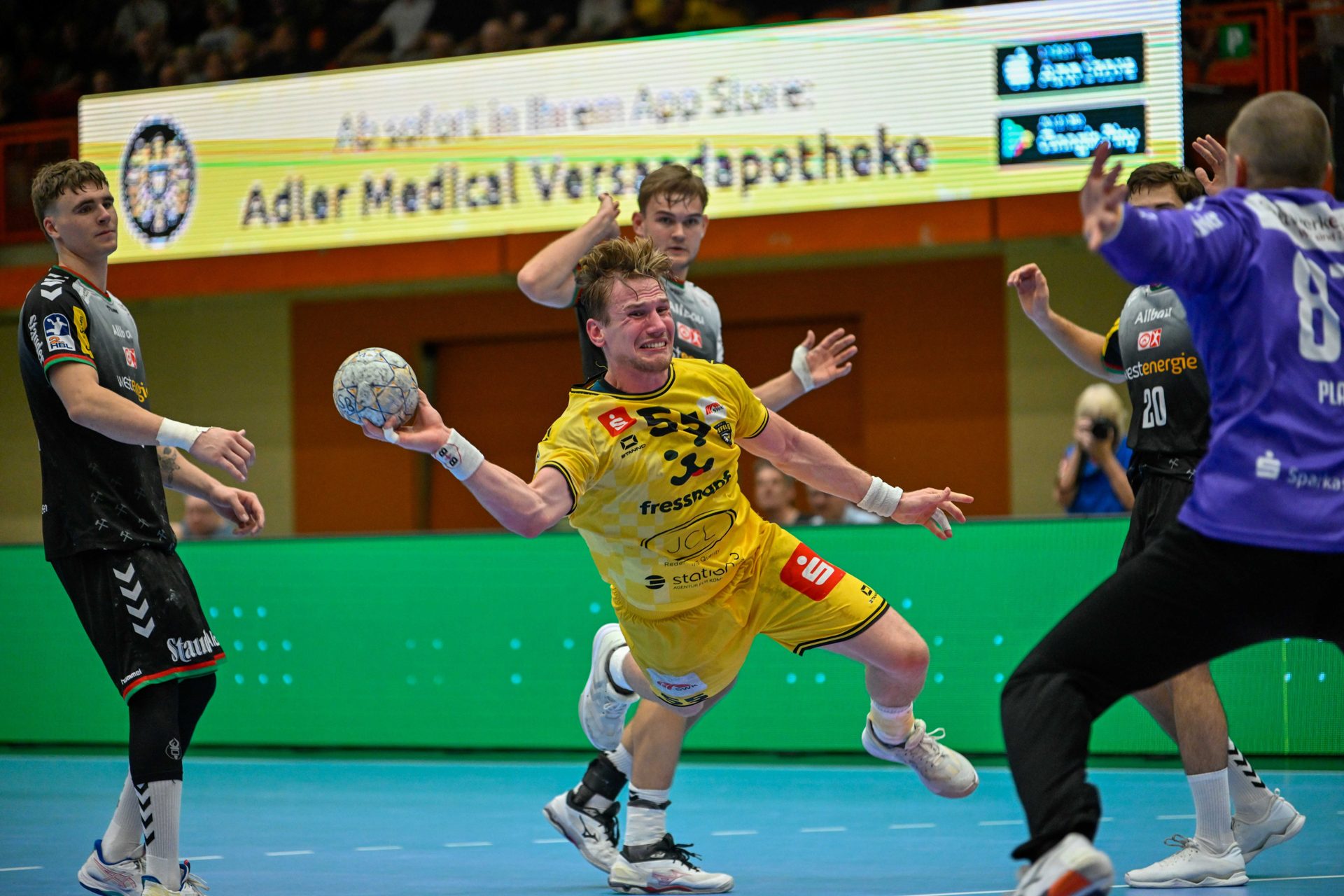 HSG-Spieler im Sprungwurf vor LED-Bande, Trikot mit Partnerlogos