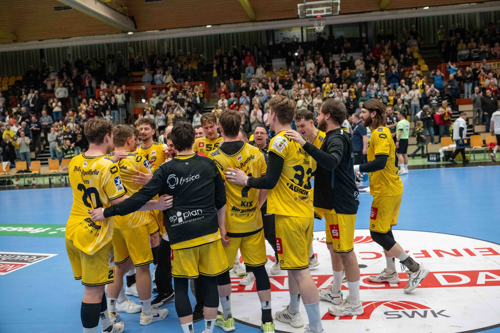 HSG-Team jubelt auf dem Mittelkreis mit Partnerlogo vor den Fans